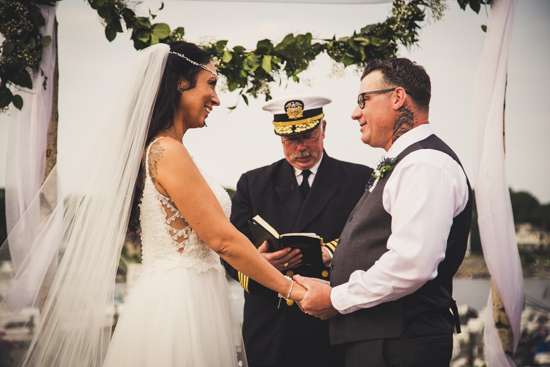 Smiling bride and groom holding hand during ceremony
